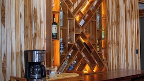 Angolo bar in legno con portabottiglie e diverse bottiglie.