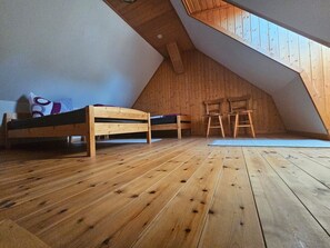 Ein Schlafzimmer im Loft-Stil mit schrägverdeckter Decke, Holzboden, zwei Stockbetten und einem Dachfenster.