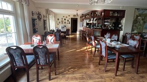 Restaurante com chão de madeira, cadeiras em formato de coração, área de bar e vista para o exterior.