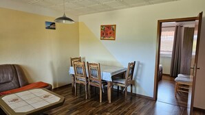 Un comedor con una mesa y sillas de madera, un techo con diseño de cuadrícula y una puerta que da a otra habitación.