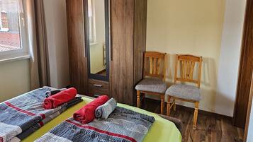 Ein Schlafzimmer mit einem Bett, zwei Stühlen, einem Kleiderschrank und einem Fenster.