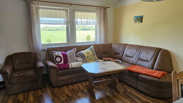Un salón con un sofá de cuero marrón, una mesa de centro de madera y una ventana con cortinas.