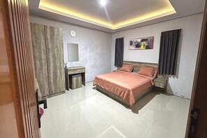 A bedroom with a bed, a bedside table, a mirror, a clock, and a painting on the wall. - Modern Suite Near Sanur Beach (Bali)