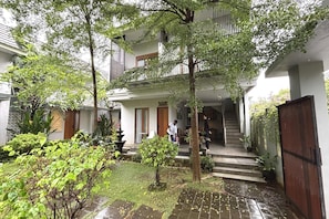 A courtyard with a staircase leading to a building entrance, surrounded by greenery and potted plants. - Modern Suite Near Sanur Beach (Bali)