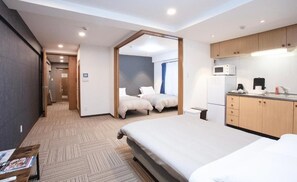 Ein Hotelzimmer mit einem großen Bett, einer Küchenzeile, einem Badezimmer und Blick auf den Flur.