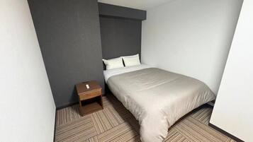 Una habitación de hotel con una cama, una mesita de noche y piso alfombrado.