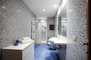 Ein Badezimmer mit Dusche, Waschbecken und Spiegel.