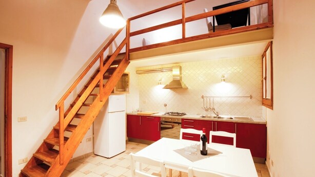 Eine Küche mit einer Holztreppe, einem Esstisch mit Stühlen und einem rot-weißen Farbschema.