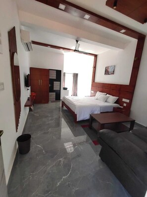 A modern bedroom with a bed, a sofa, a TV, and a wardrobe. - Vythiri Eternal Bliss (Chelode)