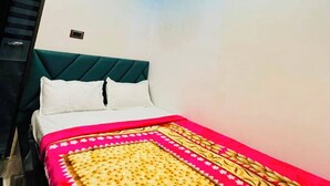 A bedroom with a bed, a ceiling fan, and a unique ceiling design. - Neelkanth PG House (Varanasi)