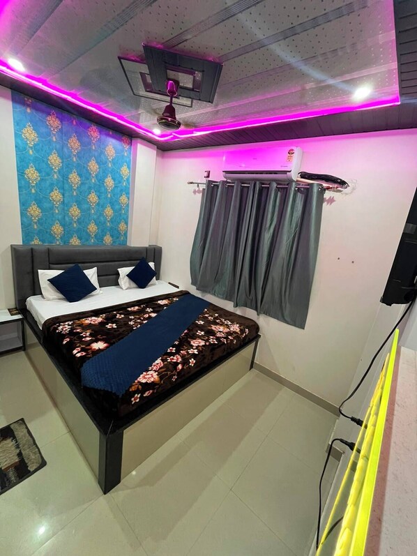 A bedroom with a bed, a ceiling fan, a window with curtains, and a wall-mounted air conditioning unit. - Neelkanth PG House (Varanasi)