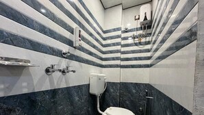 Et badeværelse med toilet, håndehåndtørrer og en spand.