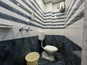Kylpyhuone, jossa on wc, käsienkuivaaja ja ämpäri.