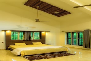 A spacious bedroom with a large bed, a ceiling fan, and windows with curtains.