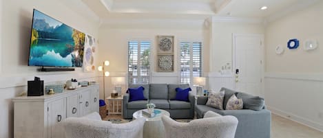 A living room with a television, sofas, and a ceiling fan.