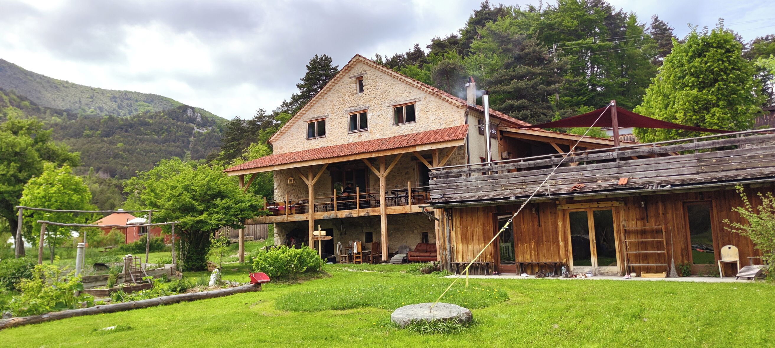 Un bâtiment rustique en pierre, doté d’un balcon et d’une extension en bois.