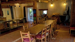Un'accogliente sala da pranzo con un lungo tavolo in legno, diverse sedie e un divano con cuscino a righe.