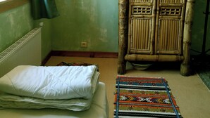 Una stanza con un letto, una grande poltrona in vimini e un tappeto decorato.