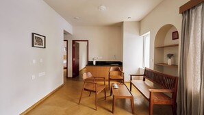 A spacious living area with a wooden dining table, chairs, a sofa, and a kitchen in the background.