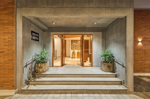 A hotel entrance with a concrete facade, a signboard, and a staircase leading to the interior.