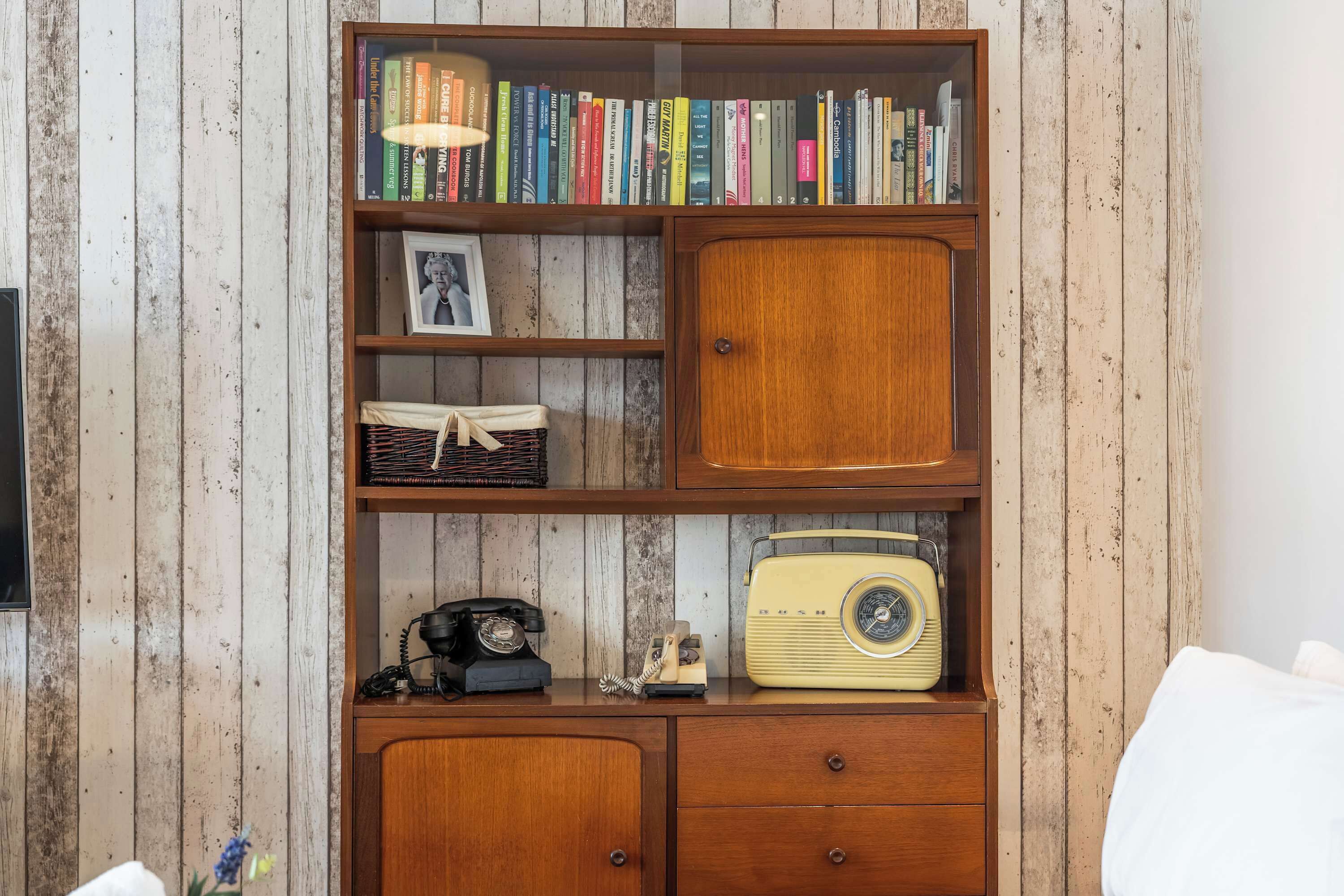 A wooden bookshelf with books, a framed photo, and a vintage radio.