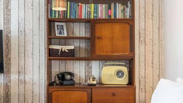 A wooden bookshelf with books, a framed photo, and a vintage radio.