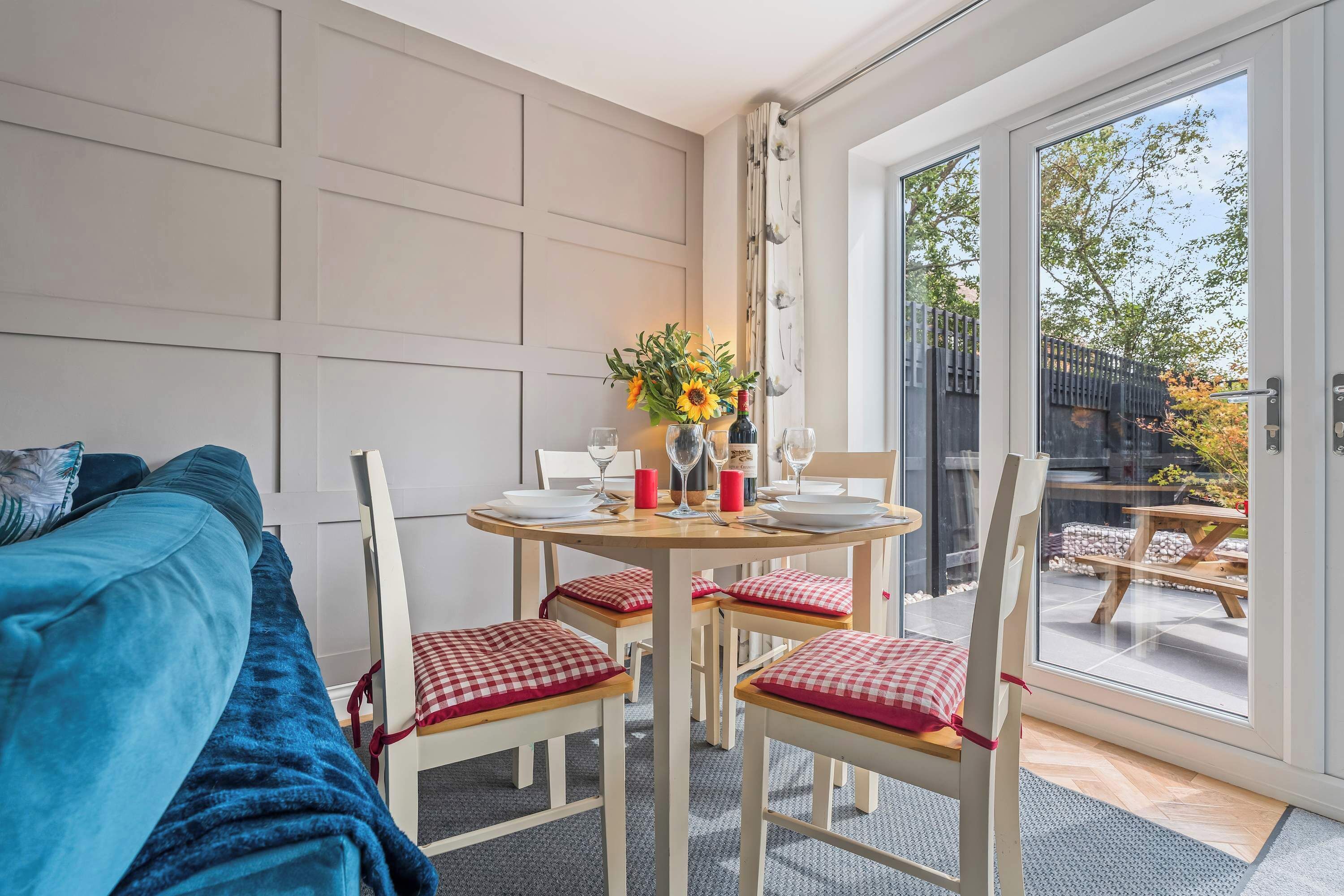 A room with a bed, a dining table set for two, and a view through a glass door to an outdoor patio.