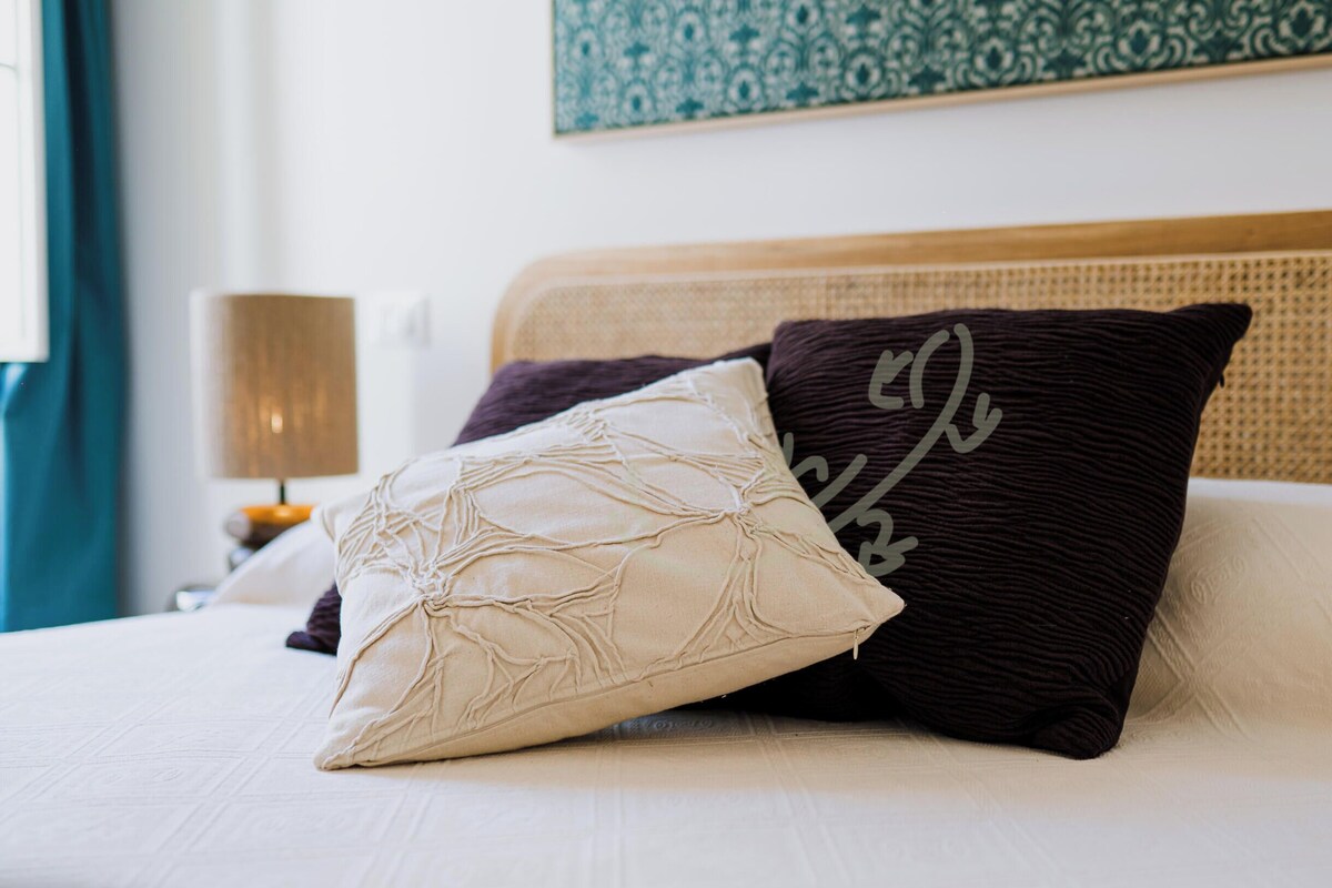 Ein Bett mit zwei Kissen, eines mit einem Kreuzmuster und das andere mit schlichtem Design.
