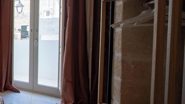 A room with a tiled floor, a wooden wardrobe, and a sliding glass door leading outside. - TD Thalia Apartments (Monopoli)