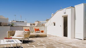 A rooftop terrace with a white chair, a small table, and a bowl of fruit. - TD Thalia Apartments (Monopoli)