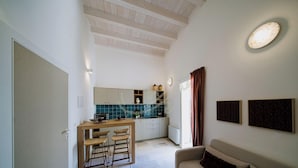 A compact kitchen with a dining area, a built-in microwave, and a window with curtains. - TD Thalia Apartments (Monopoli)