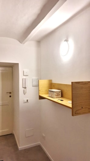 En gang med en dør, en vægtelefon og en hylde med en kasse.