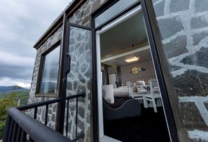 A stone building with a balcony, a bed with a headboard, and a bedside table. - Mahaeliya Rock Castle (Nuwara Eliya)