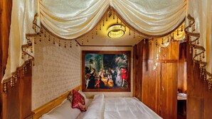 Une chambre avec un grand lit, un tableau au mur et un lustre.