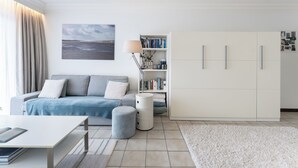 Un salon moderne comprenant un canapé, une table basse, une bibliothèque et une grande armoire.