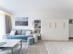 Ein modernes Wohnzimmer mit einer Couch, einem Couchtisch, einem Bücherregal und einem großen Kleiderschrank.