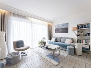 A modern living room with a sofa, armchair, coffee table, and a bookshelf. - Silver at the beach by Interhome (De Haan)