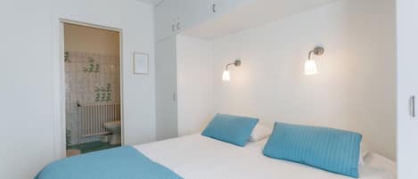 Een slaapkamer met een bed, twee bedlampen, een deur naar een badkamer, en een gecertificeerde oorkonde aan de muur.