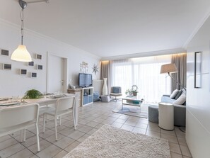 A modern living room with a dining area, a TV, and a sofa.