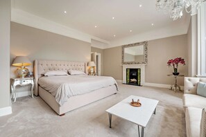 Ein geräumiges Schlafzimmer mit einem großen Bett, einem Kamin, einer Kristallleuchter und einem Couchtisch.