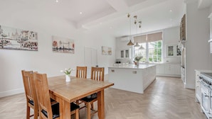 Een ruime keuken met een centraal eiland, een houten eettafel en stoelen.
