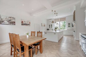 Eine geräumige Küche mit Kochinsel, Esstisch aus Holz und Stühlen.