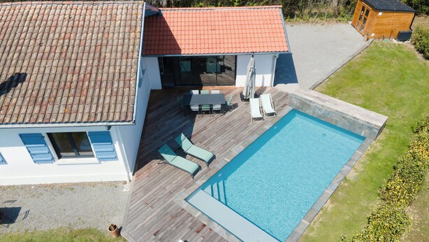 Ein Wohnhaus mit Schwimmbad, einer Sonnenterrasse und einem separaten Holzgebäude.