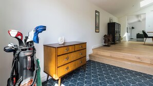 Ein Zimmer mit einem Holzkasten, einer Golfbag und einer Treppe, die in einen anderen Bereich führt.