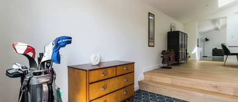 A room with a wooden dresser, a golf bag, and a staircase leading to another area.