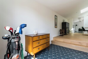 Ein Zimmer mit einem Holzkasten, einer Golfbag und einer Treppe, die in einen anderen Bereich führt.