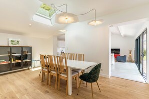 Ein moderner Essbereich mit einem weißen Tisch, Holzstühlen und einer außergewöhnlichen Deckenleuchte.