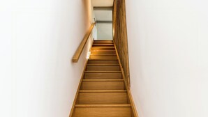 Eine Holztreppe mit Handlauf und einer Lampe am oberen Ende.