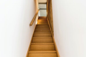 Eine Holztreppe mit Handlauf und einer Lampe am oberen Ende.