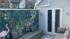 Un patio con una zona de estar, un mural de fauna y un ventanal corredera.